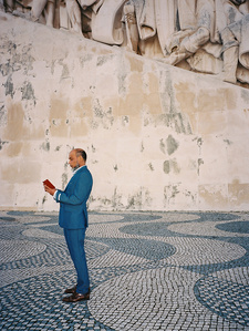 A man in a blue suit in front of Monument of the Discoveries in Belem, Lisbon.
Un homme en costume bleu devant le Monument aux découvertes à Belem, Lisbonne.