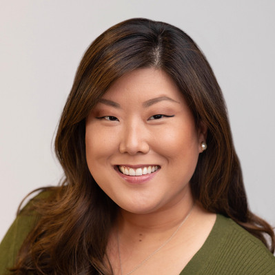 A Corporate headshot of a smiling Asian woman with long brown hair, wearing pearl earrings, a gold heart charm necklace, a moss green sweater, and a white inner garment at the Astho Conference 2023 in Crystal City, VA.
http://www.annanproductions.com/