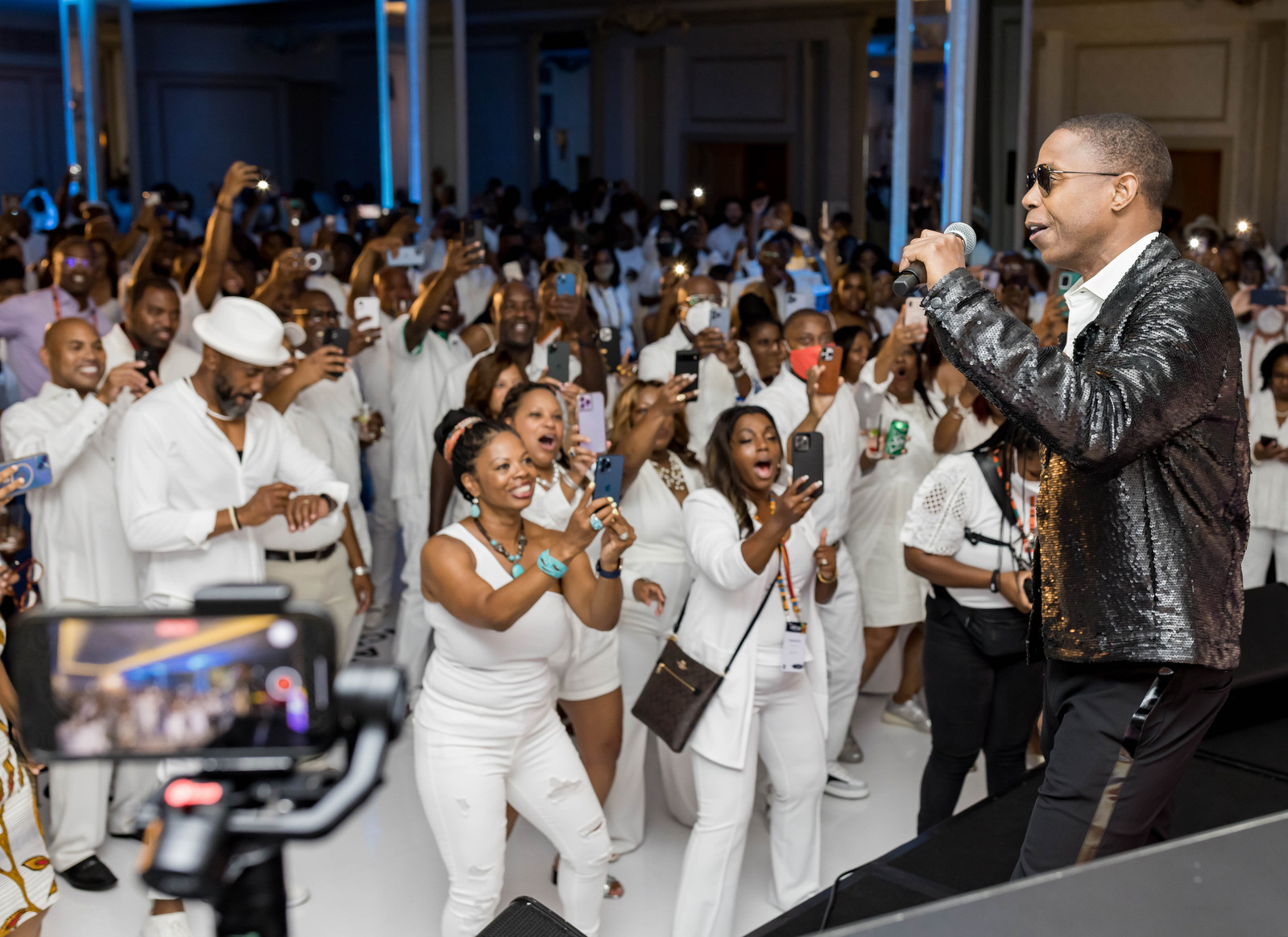A diverse crowd of black individuals dancing to a male black artist singing on stage at the 16th CAAFP Event 2022. 