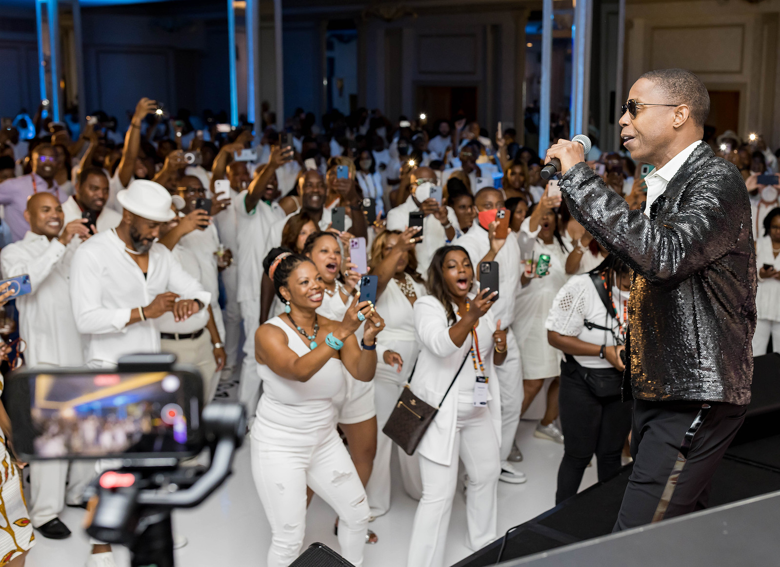 A diverse crowd of black individuals dancing to a male black artist singing on stage at the 16th CAAFP Event 2022. 