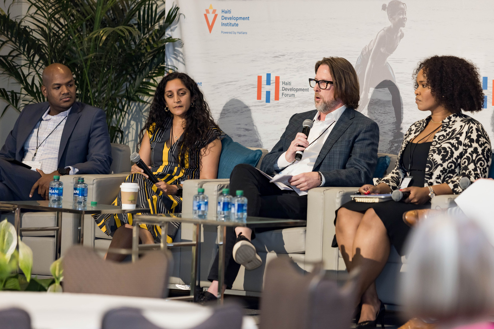 A four-speaker panel at the Haiti Development Forum consisted of a bald black man, an East Asian woman with curly black hair, a white man with glasses, and a black woman with short, tight curls.