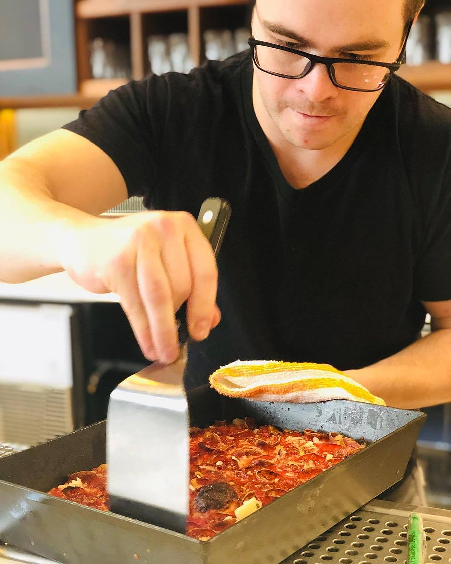 Pizza chef cutting hand thrown pizza pie