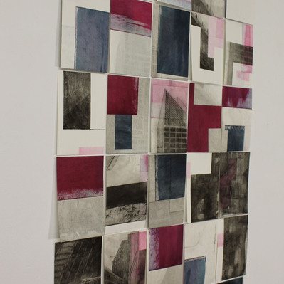 A grid of small prints on a white wall. The prints are mainly black, white, and fuchsia, with a smattering of dark blue-green.
