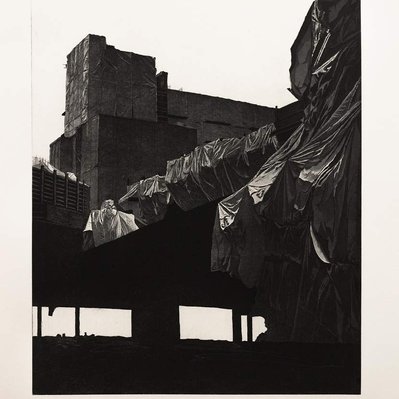 A monochromatic black and white structure wrapped in tarps, held aloft on a concrete pillar.