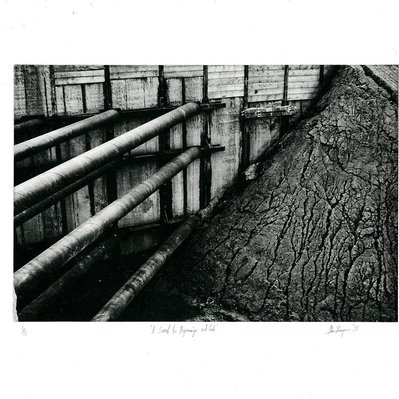 A construction excavation, with a heap of dirt occupying the entire right side, broken up by eroded rivulets, and on the left a set of steel pipes bracing the corner of the excavation.