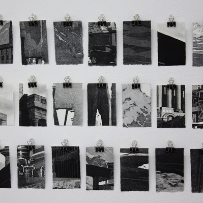 A grid of 21 small fragments of architectural illustrations, showing road surfaces, mountainsides, clusters of windows, and columns. They are black and white, hung on a white wall with small clips.