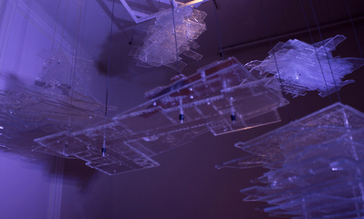 Several floating blocks of transparent sheets in various shapes, with engraved lines of maps and architectural plans on them. They are illuminated by a dramatic purple light.