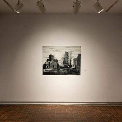 The three previous prints, installed in a gallery space with white walls and a red-orange tiled floor. The artworks are each illuminated by a spotlight.