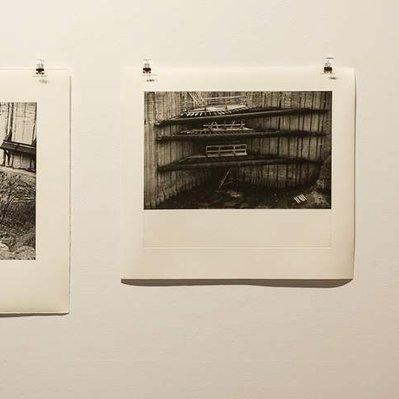 An installation view of three prints of construction excavations in a gallery, on a white wall.