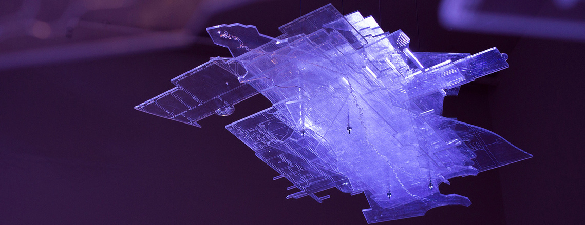 A floating block of transparent sheets in various shapes, with engraved lines of maps and architectural plans on them. They are illuminated by a dramatic purple light.