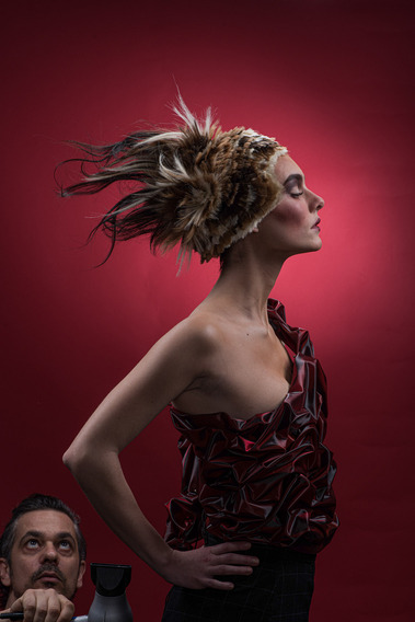 Model posing with fierce Spartan armor and artistic hairstyle in a studio, capturing creativity and strength