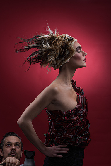 Model posing with fierce Spartan armor and artistic hairstyle in a studio, capturing creativity and strength