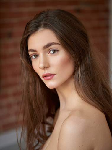 Close-up of a model with minimal makeup, showcasing her natural beauty and glowing skin.