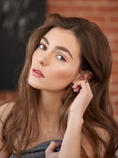 Natural beauty captured in a soft, candid photo, highlighting the model's features in a natural, unposed moment.