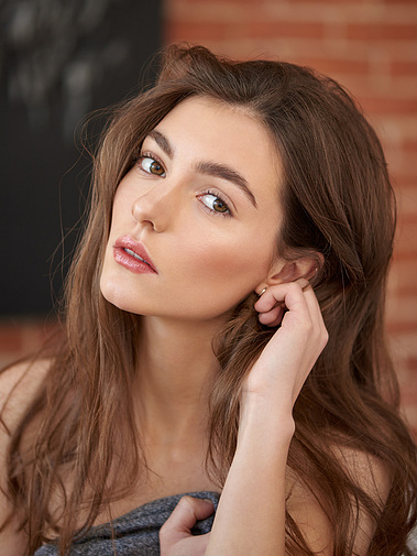 Natural beauty captured in a soft, candid photo, highlighting the model's features in a natural, unposed moment.