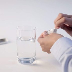 Wasserglas mit Hand und Tablette