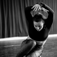 Young woman kneeling  and arms up in dance pose  with grace and effortlessness in soft light