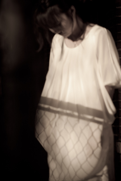 Young Korean young woman in contrasty outdoor scene with light dress and shadows covering her