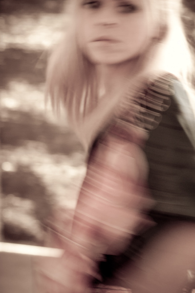 Young pale-looking woman in blurry setting looks back over her shoulder as she moves