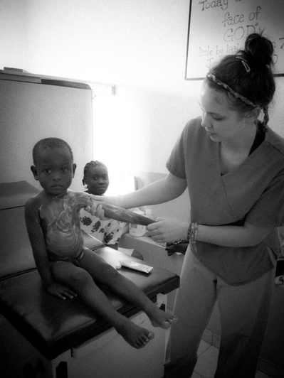Haitian child being treated by a nurse as another child looks at the camera