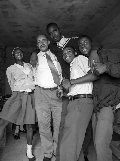 A group of smiling students and their teacher in Haiti pose for a relaxed portrait
