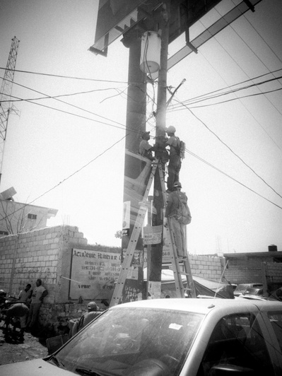 Electrical workers fix power lines on a street in Haiti
