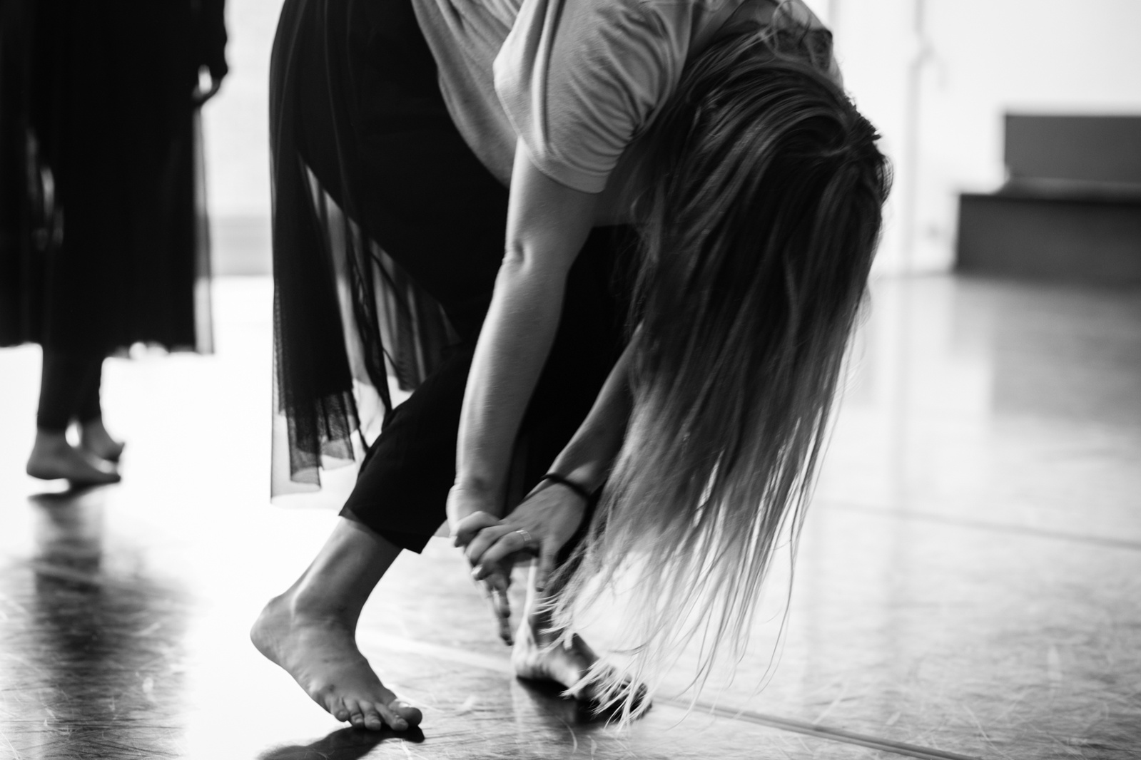 Detail of dancer bowing down during a dance routine, hair flowing down concealing her face