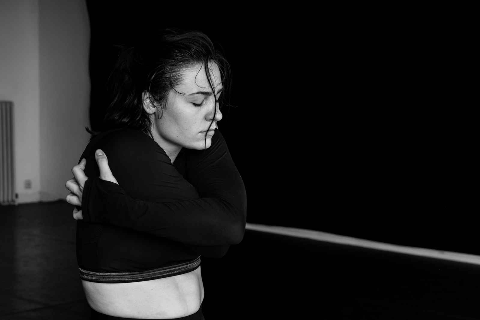 Close up of pale skinned dancer revealing her belly and embracing herself with eyes closed while dancing 