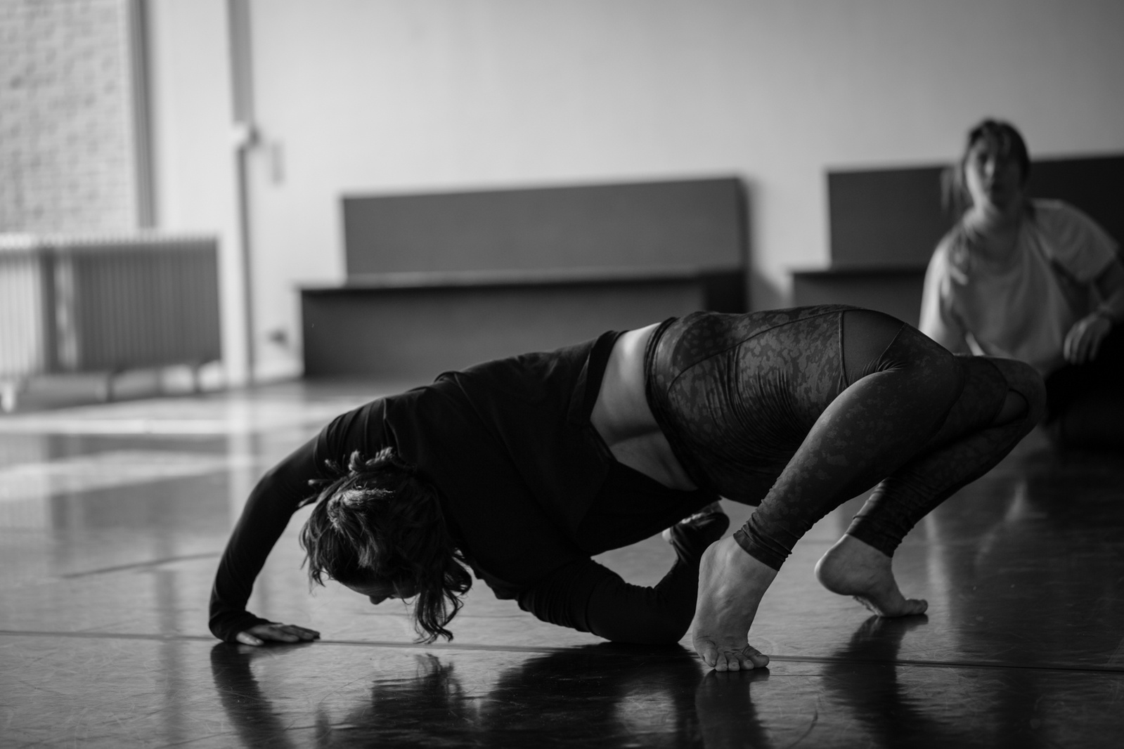 Young woman dancing bending over her back while other dancer watches her