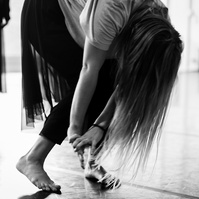 Detail of dancer bowing down during a dance routine, hair flowing down concealing her face