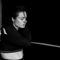Close up of pale skinned dancer revealing her belly and embracing herself with eyes closed while dancing 