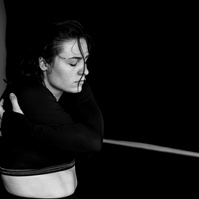 Close up of pale skinned dancer revealing her belly and embracing herself with eyes closed while dancing 