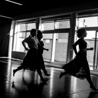 Three young women in motion running in a dance studio with large window behind them
