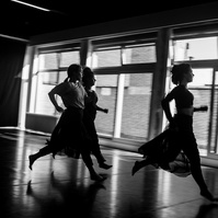 Three young women in motion running in a dance studio with large window behind them