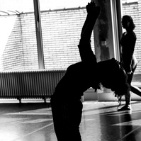 Silhouette of dancer bending backwards during dance routine with large window behind her
