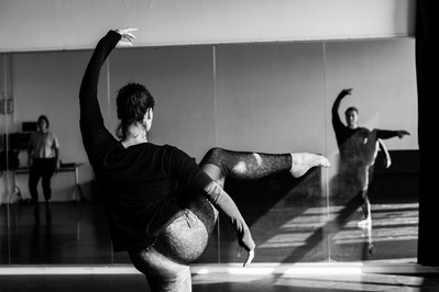 Young woman dancing with lifted arm and leg, looking at herself in the mirror observing her form