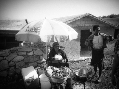 Haitian female street food vendors waiting for customers shaded by an umbrella
