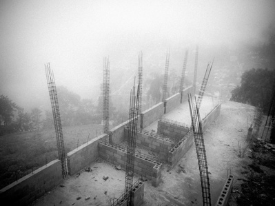 A concrete foundation for a building high in the mountains surrounded by clouds in Haiti seen from a birds-eye view
