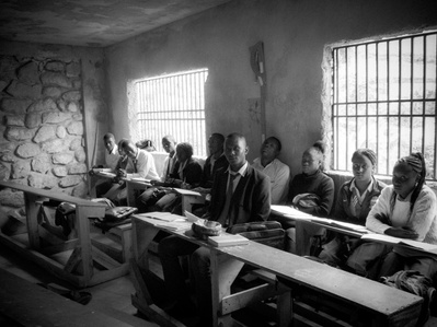 Haitian students in a dimly lit classroom gaze at the camera