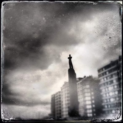 Black and white iPhone tintype of a statue in Belgian city on a cloudy day, shot from below