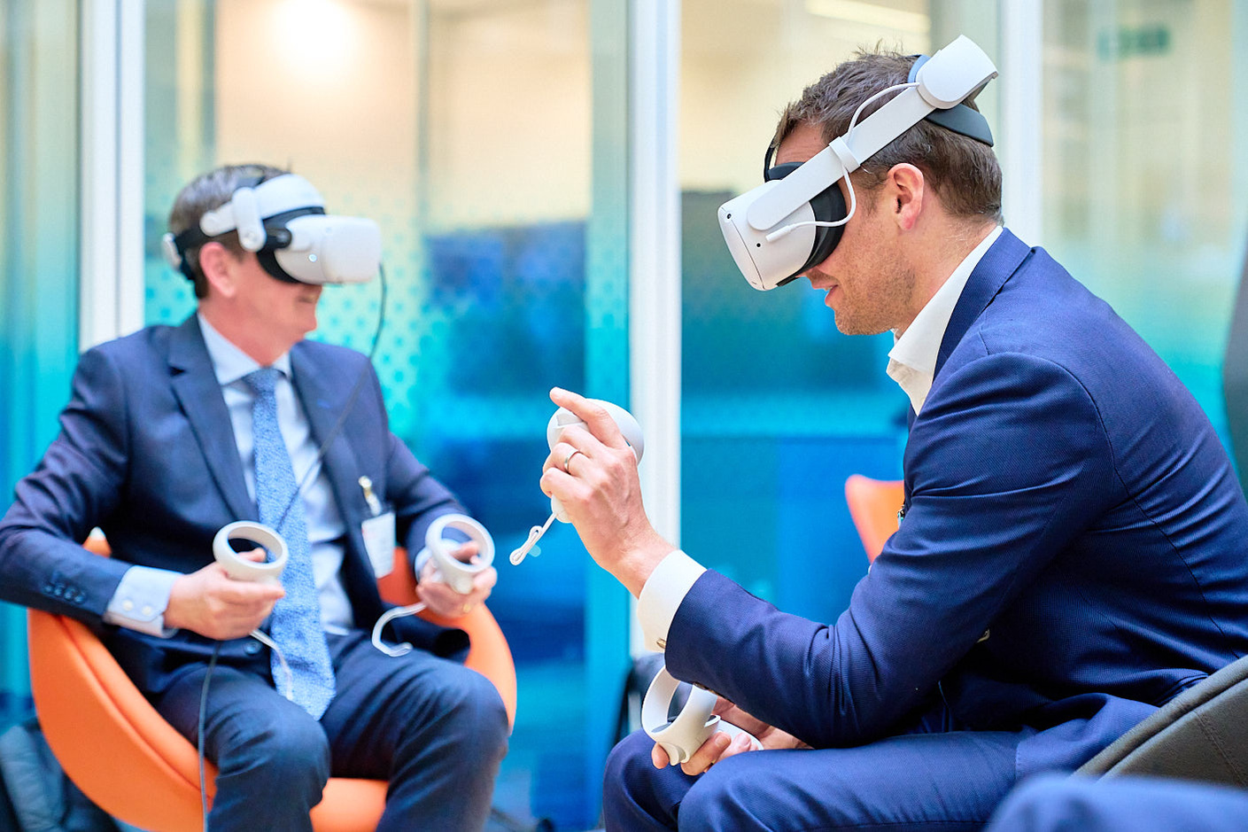 Photography of men in suits using VR headsets at a panel discussion for investments in tech.