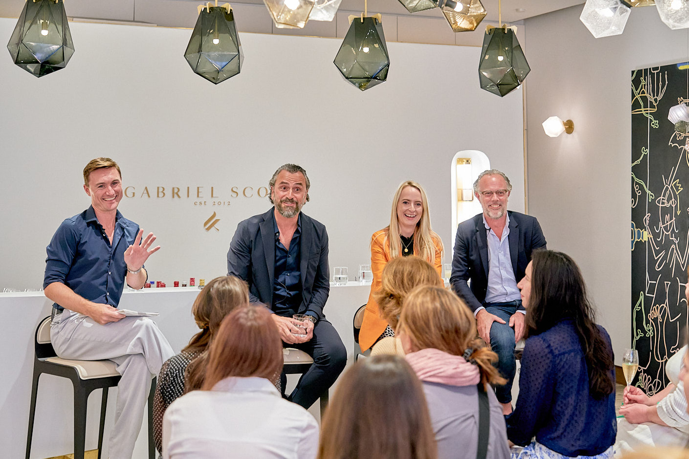 Hamish Kilbun, Alessandro Munge & Scott Richler sitting on chairs in a room at a corporate event in Mayfair, London.