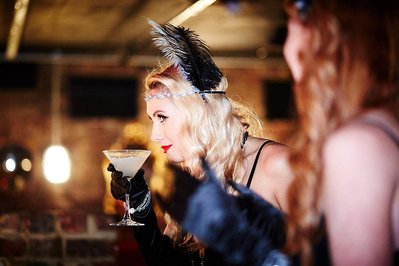 Luxury corporate party event photography by photographer Josh Caius in Mayfair, London. This is a photo of a woman at an end of year event for her company, drinking cocktails in fancy dress.