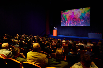 Museum and art gallery photographer Josh Caius photographing a talk in London. Wide shot of audience reacting to the speaker on stage.