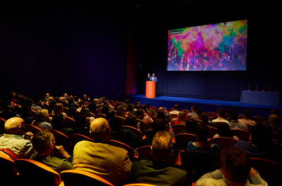 Museum and art gallery photographer Josh Caius photographing a talk in London. Wide shot of audience reacting to the speaker on stage.