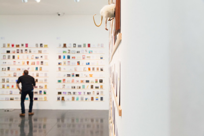 Royal College of Art event PR photography by Josh Caius. Installation shot of secret postcards exhibition in London, with a person in it.