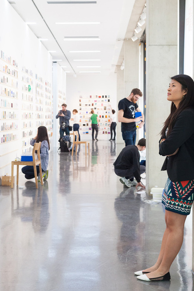Royal College of Art event PR photography by Josh Caius. Installation shot of secret postcards exhibition in London, with a person in it.