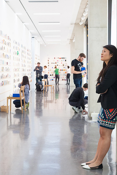 Royal College of Art event PR photography by Josh Caius. Installation shot of secret postcards exhibition in London, with a person in it.