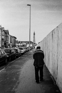A man walks along a sand strewn street towards Blackpool tower.
Photograph from the series To Live and Die in Lancashire: Wet Paint by Matthew James Fleming. Taken with a Leica M6 and Ilford HP5 35mm film.