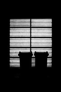 Two bins are silhouetted by light from a garage door behind, Clitheroe. 
Photograph from the series To Live and Die in Lancashire: Wet Paint by Matthew James Fleming. Taken with a Leica M6 and Ilford HP5 35mm film.